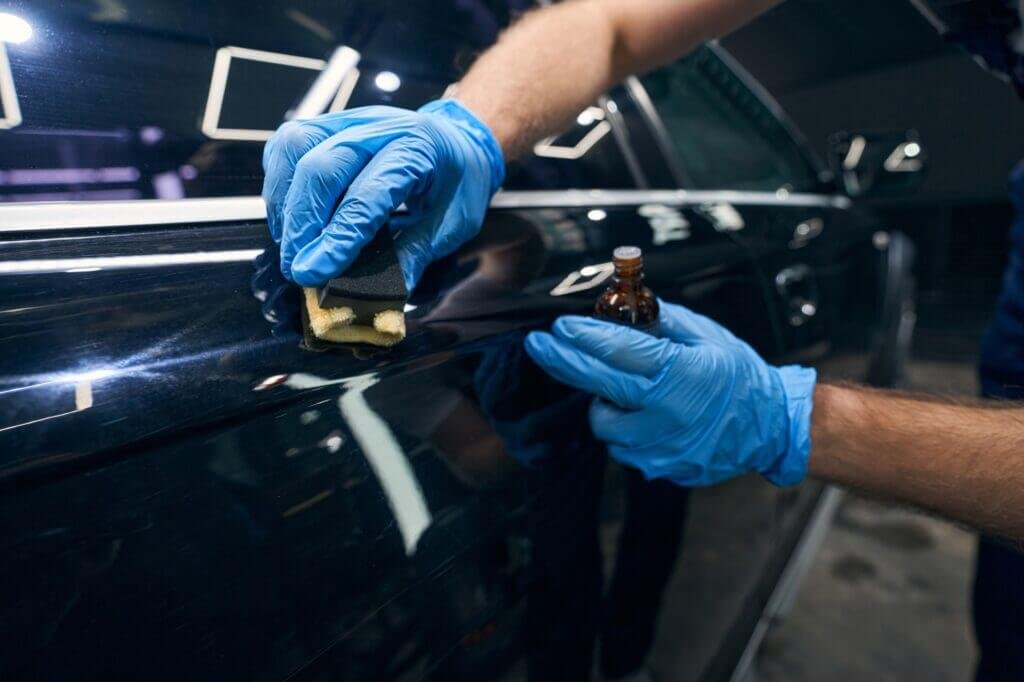 Person applying coating on car surface scratches